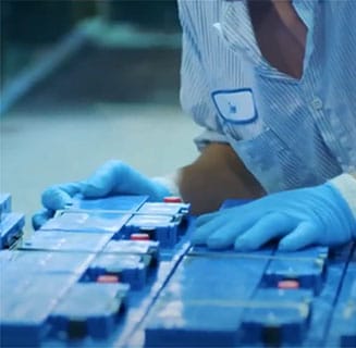 Lead battery manufacturing employee pushing new batteries together on production line.