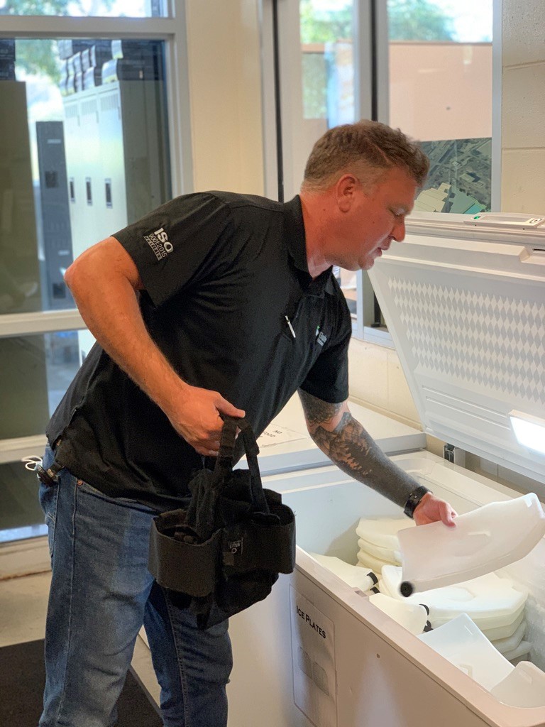 Employee putting on ice vest to prevent heat stress.