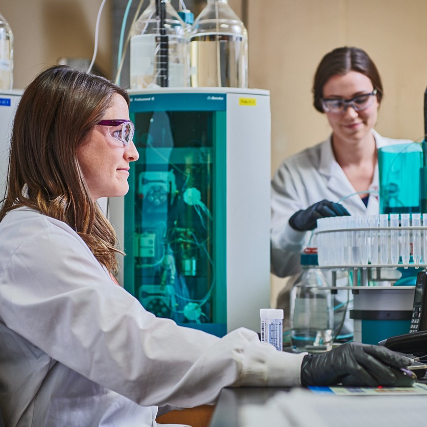 Two women working in a lab at a lead battery recycling facility.