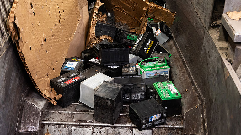Spent lead acid batteries on a conveyer for lead battery recycling.