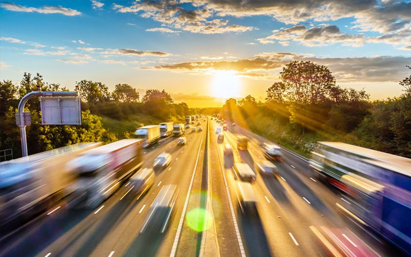 Blurred highway traffic and a sunrise demonstrating the essential nature of lead batteries to power our lives.