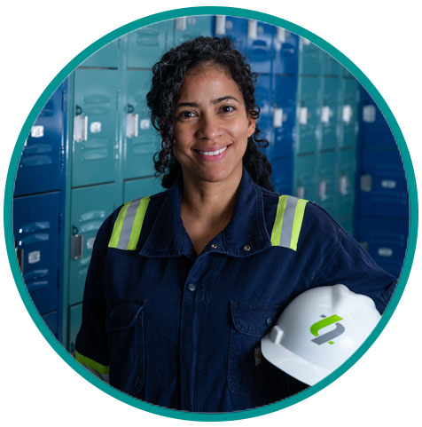 Lead battery recycling facility employee smiling and holding a safety hard hat standing in a locker room.