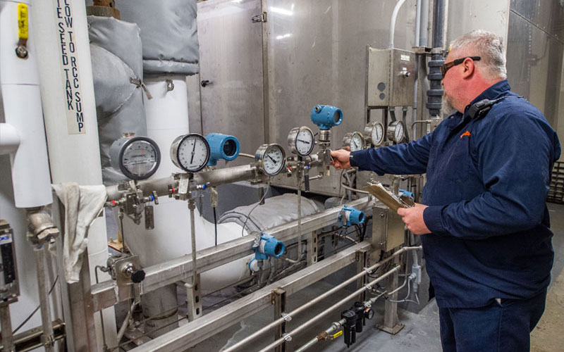 Lead battery recycling employee checking gauges to monitor systems for environmental health and safety.